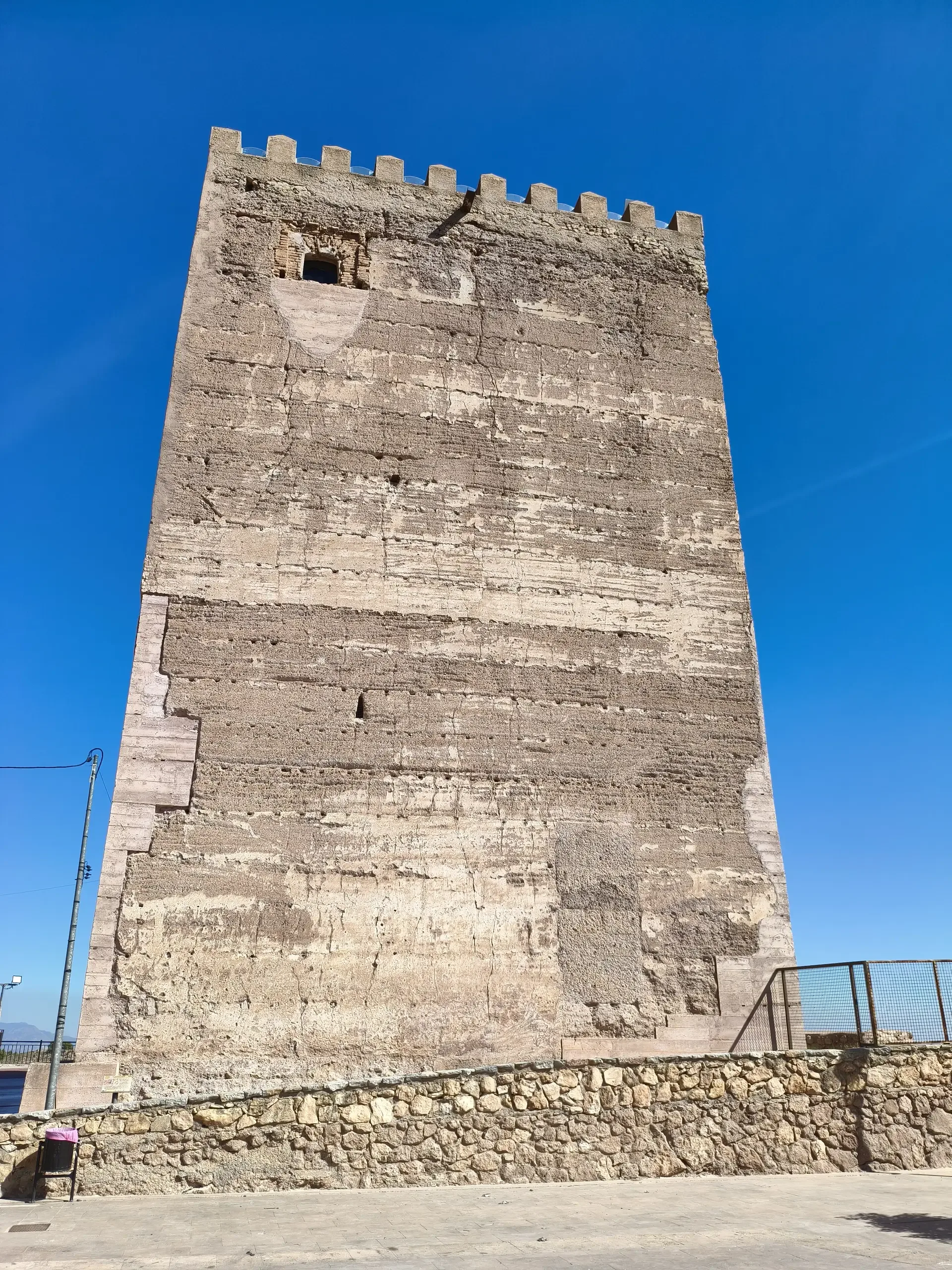 Tall stone wall and crenellated top of Aledo's Torre del Homenaje