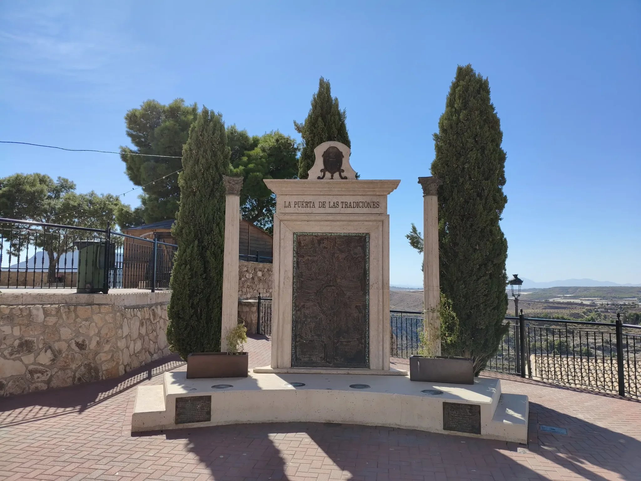 Stone monument and cypress trees beside the viewpoint at Aledo Castle