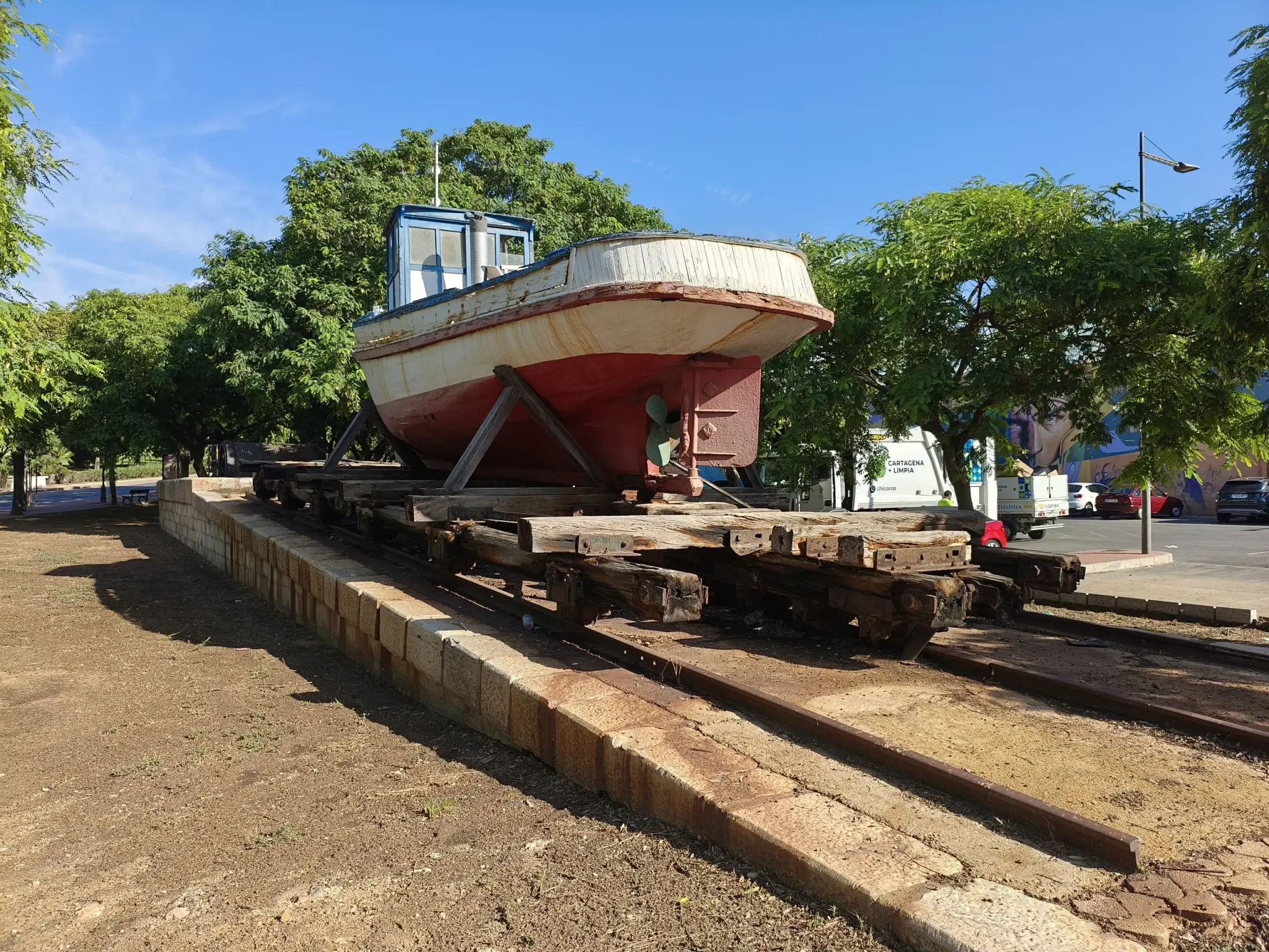 Bateau de pêche traditionnel exposé à terre sous des arbres matures