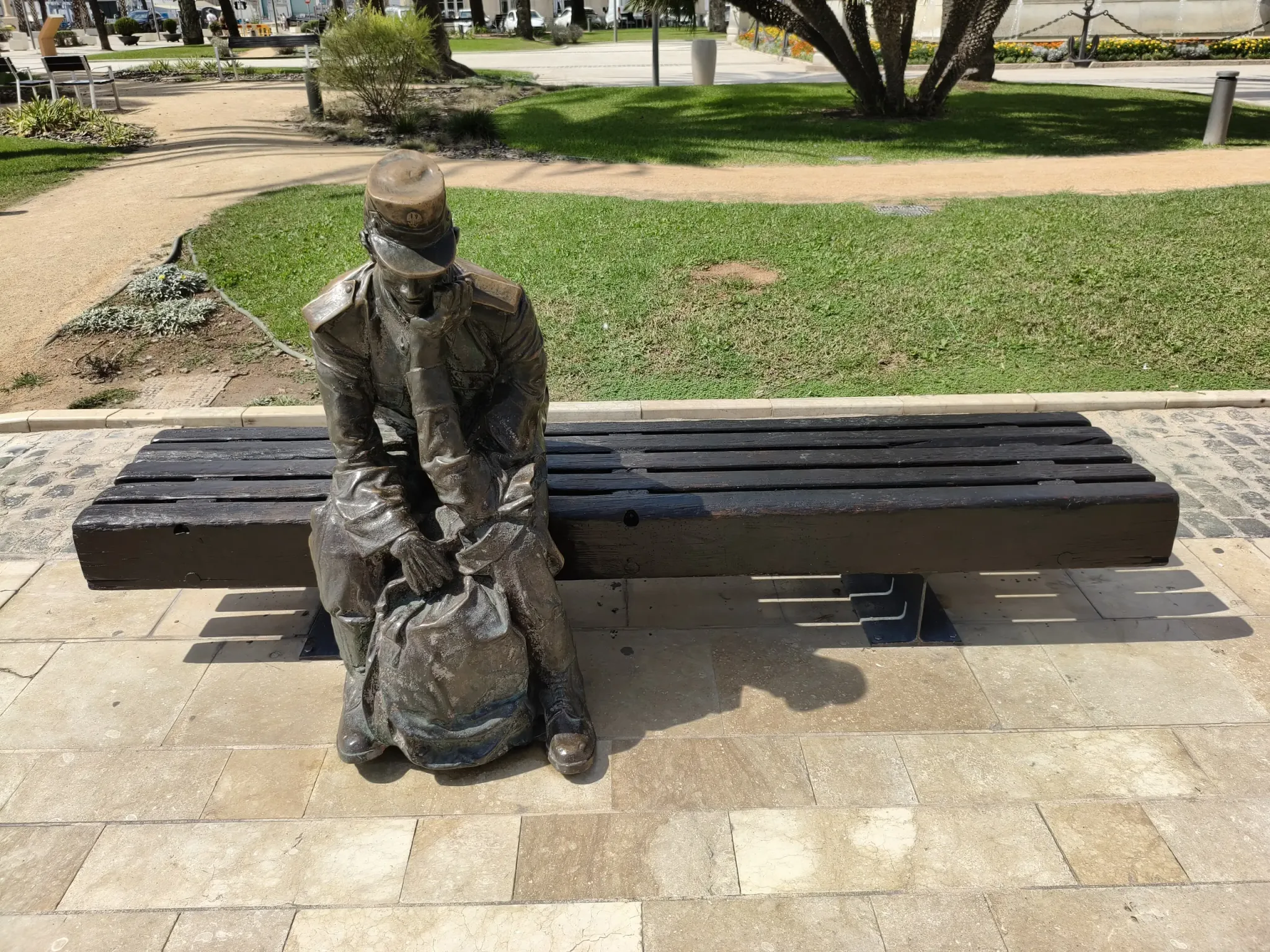Figure en bronze assise à côté d'un banc sur une place de Carthagène