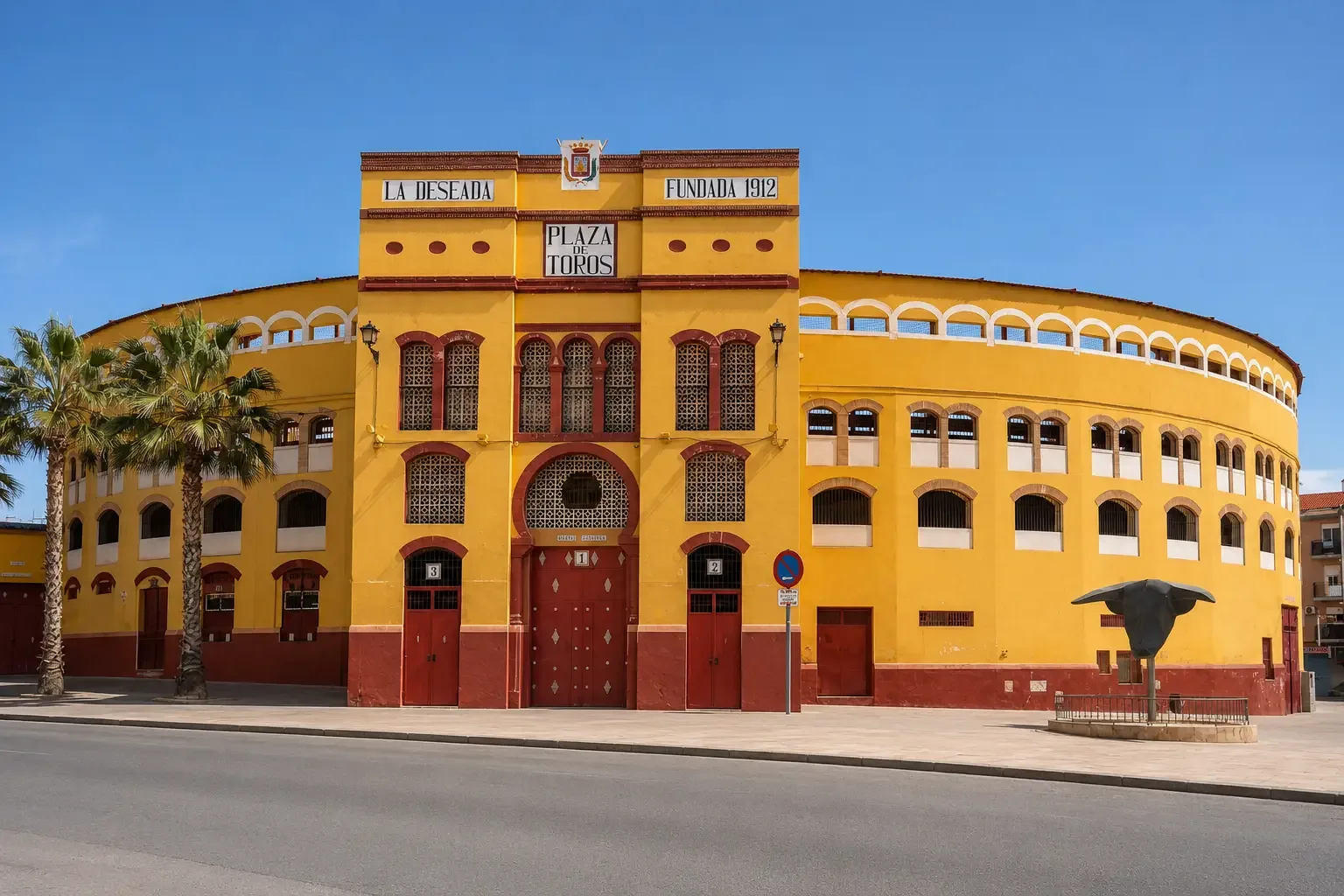 Yellow and red curved exterior of La Deseada bullring in Cieza