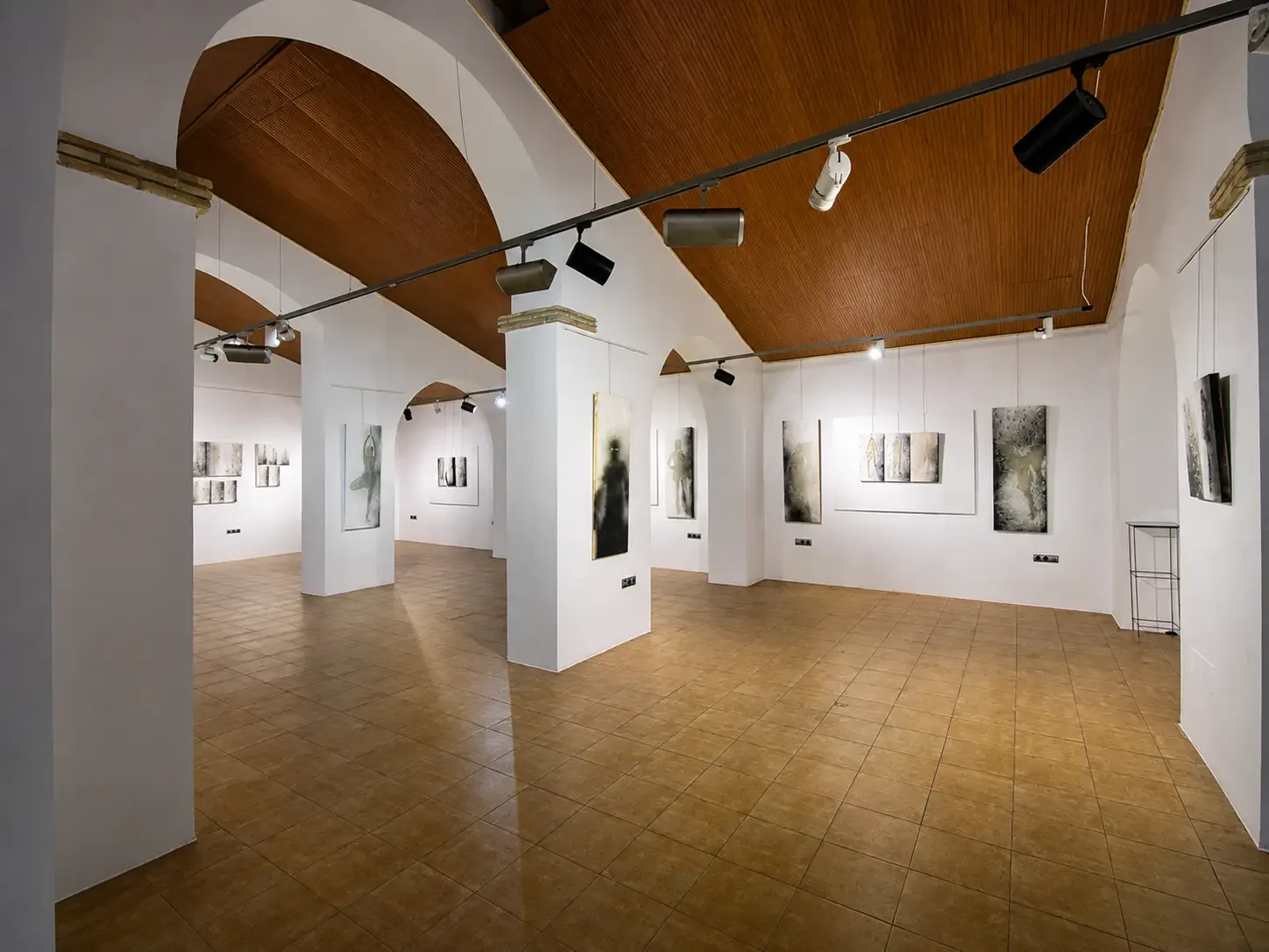 White-walled exhibition gallery inside El Pósito with artworks displayed between arches