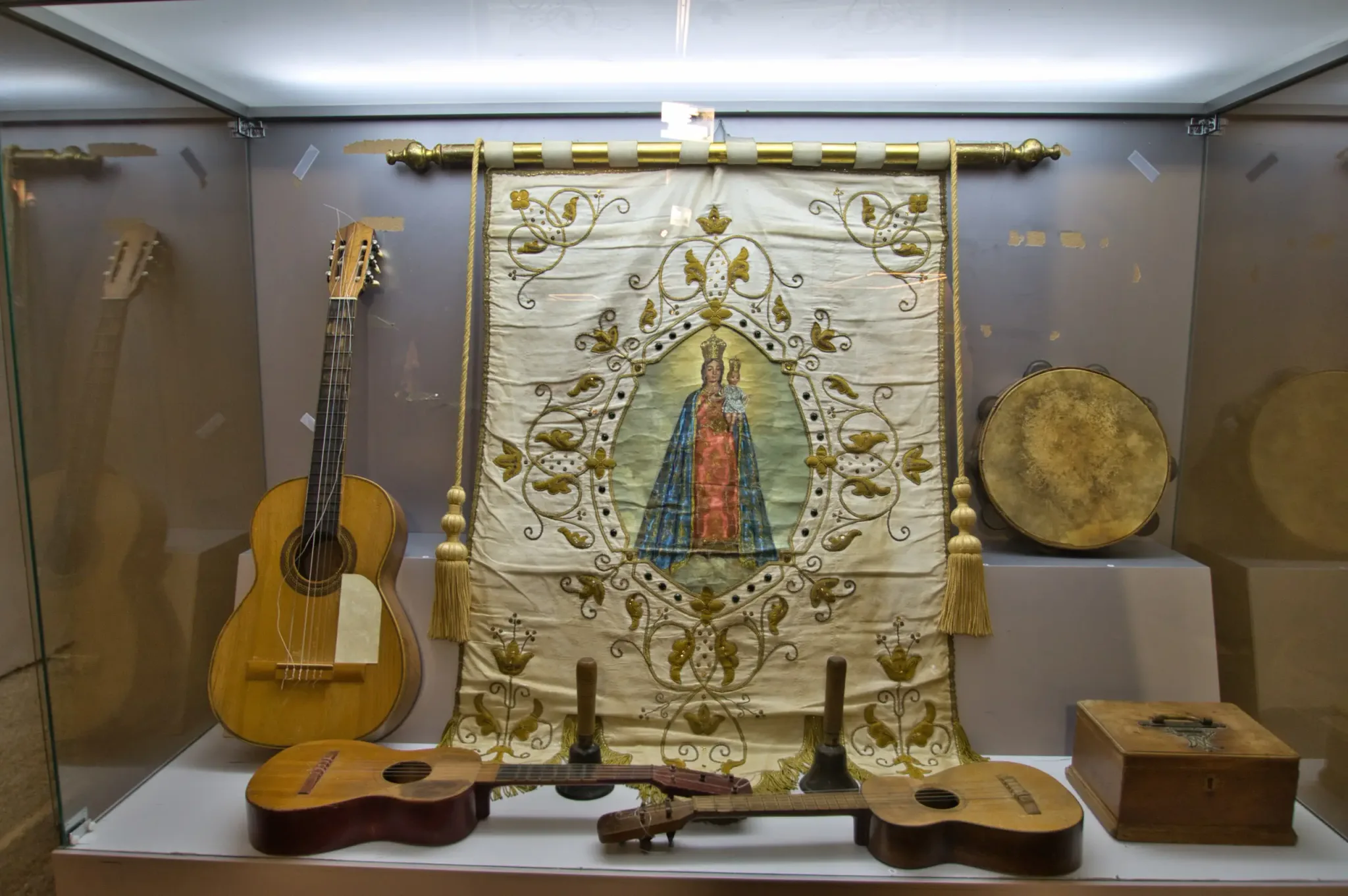 Embroidered religious banner, guitars and drum displayed inside El Pósito