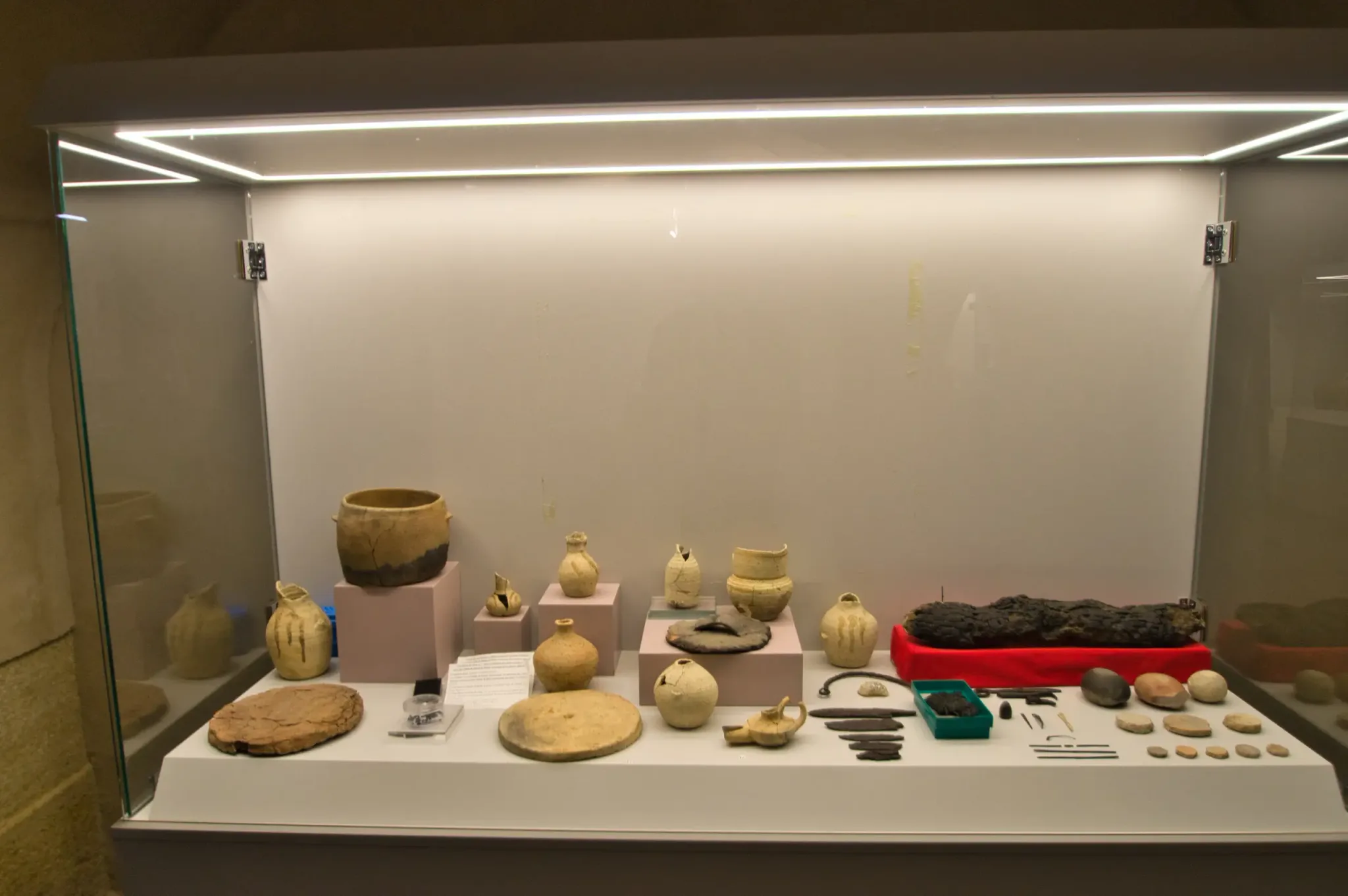 Pottery, metal objects and other archaeological finds in a glass exhibition case