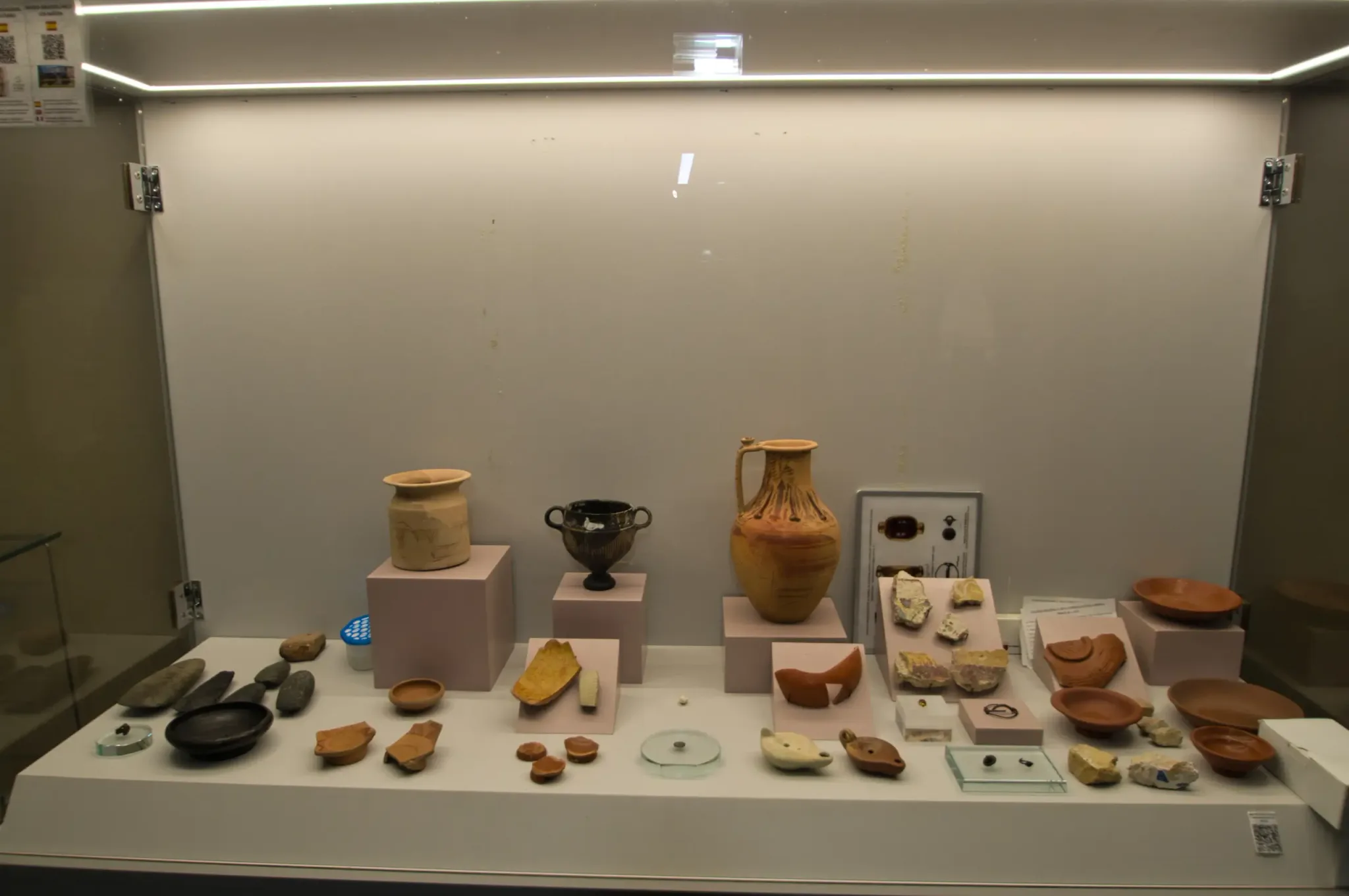 Ceramic vessels and small archaeological finds arranged in a museum-style display case