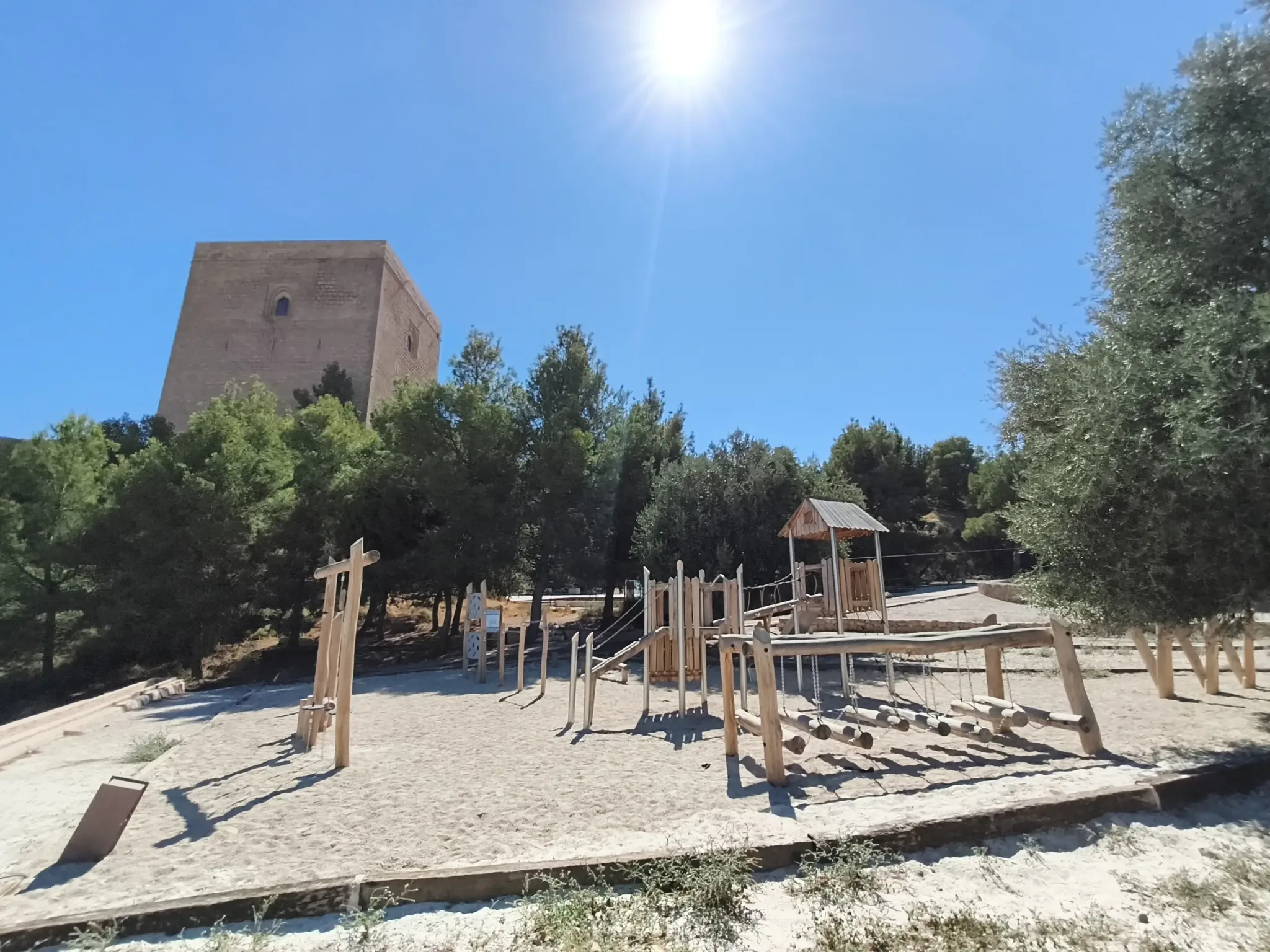 Zone d'activités extérieure en bois sous une tour du château sous un soleil éclatant