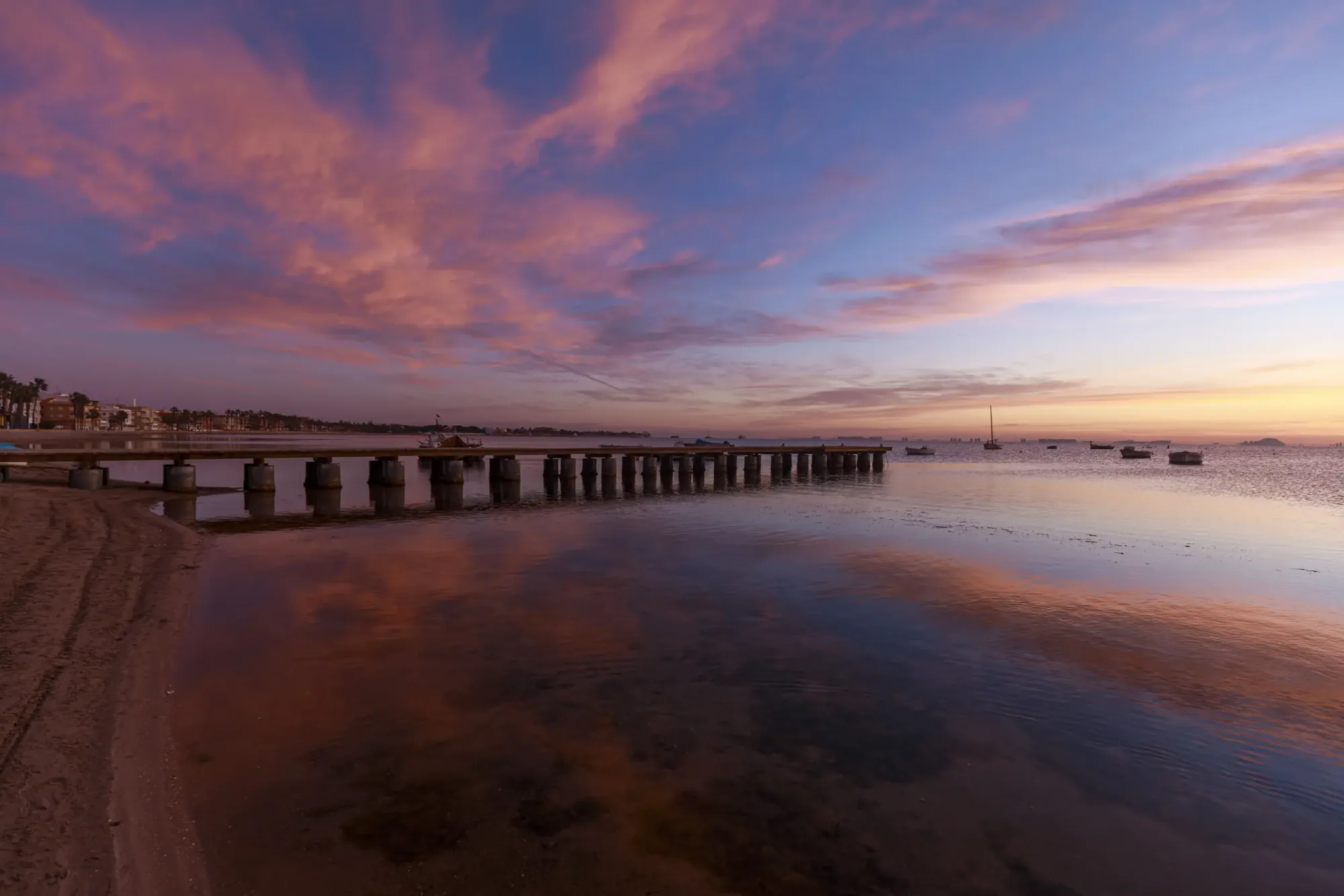 Sonnenuntergang über einem Steg und kleinen Booten im Mar Menor bei Los Alcázares