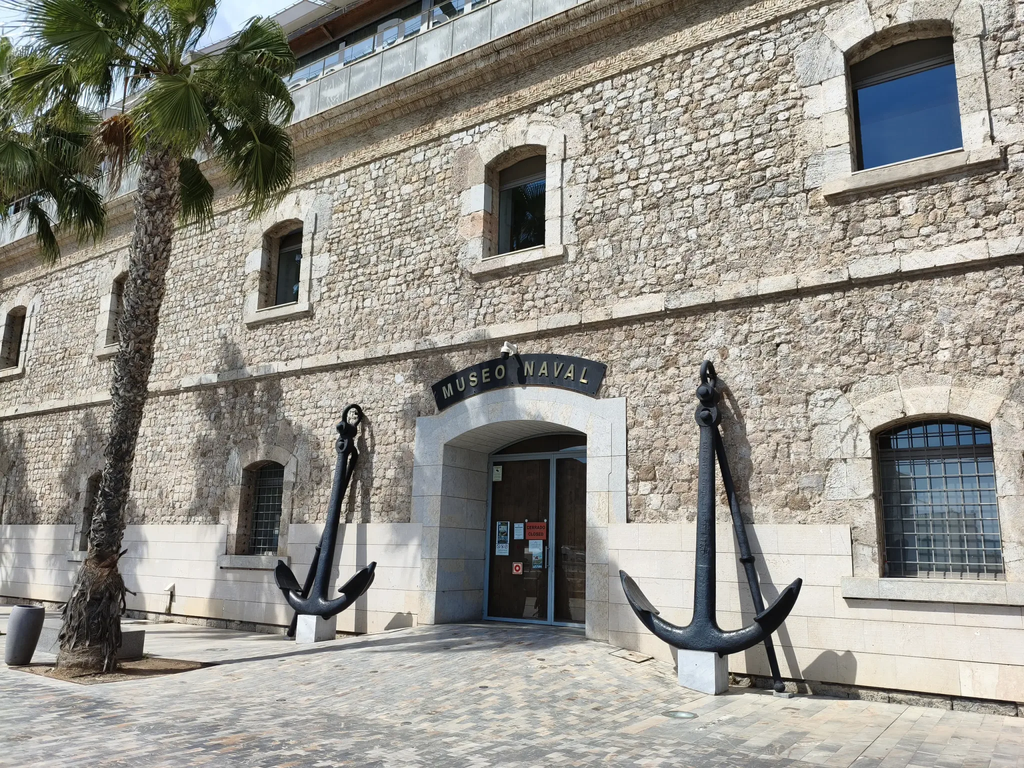 Stone entrance facade of the Naval Museum of Cartagena with large anchors on either side