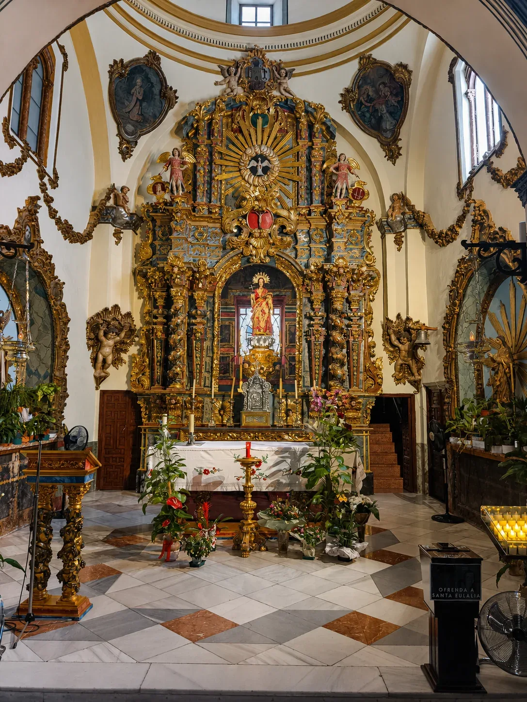 Ornate gilded main altar and flower arrangements inside Santa Eulalia Sanctuary