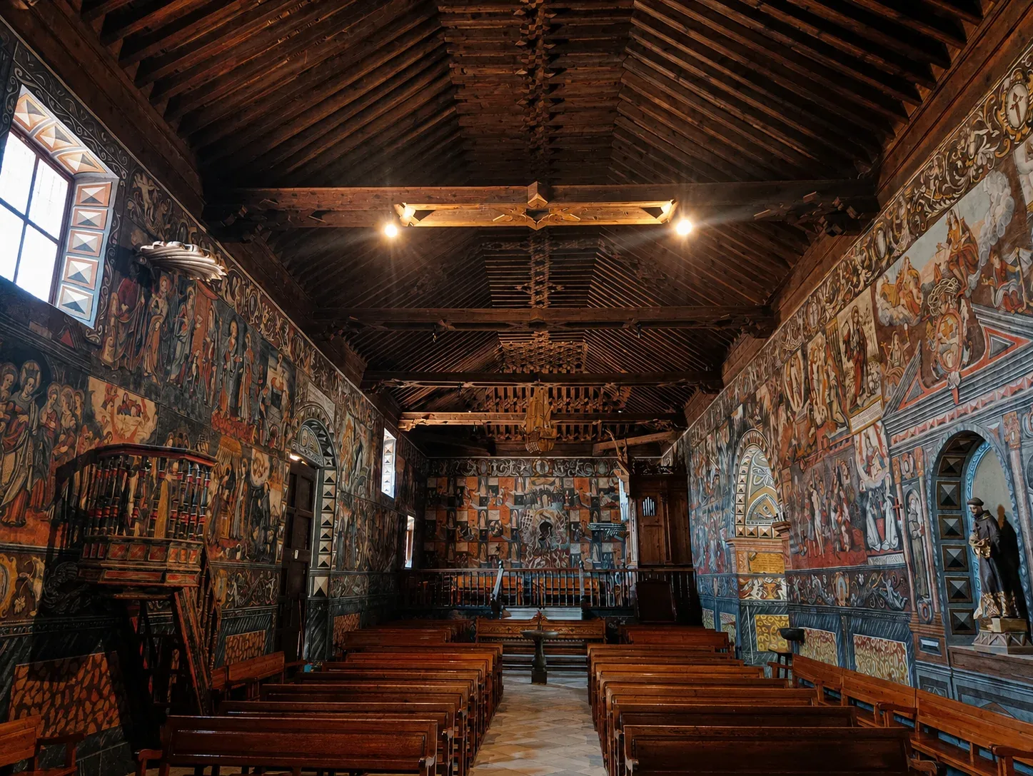 Painted nave, wooden pews and carved ceiling viewed towards the rear of the sanctuary