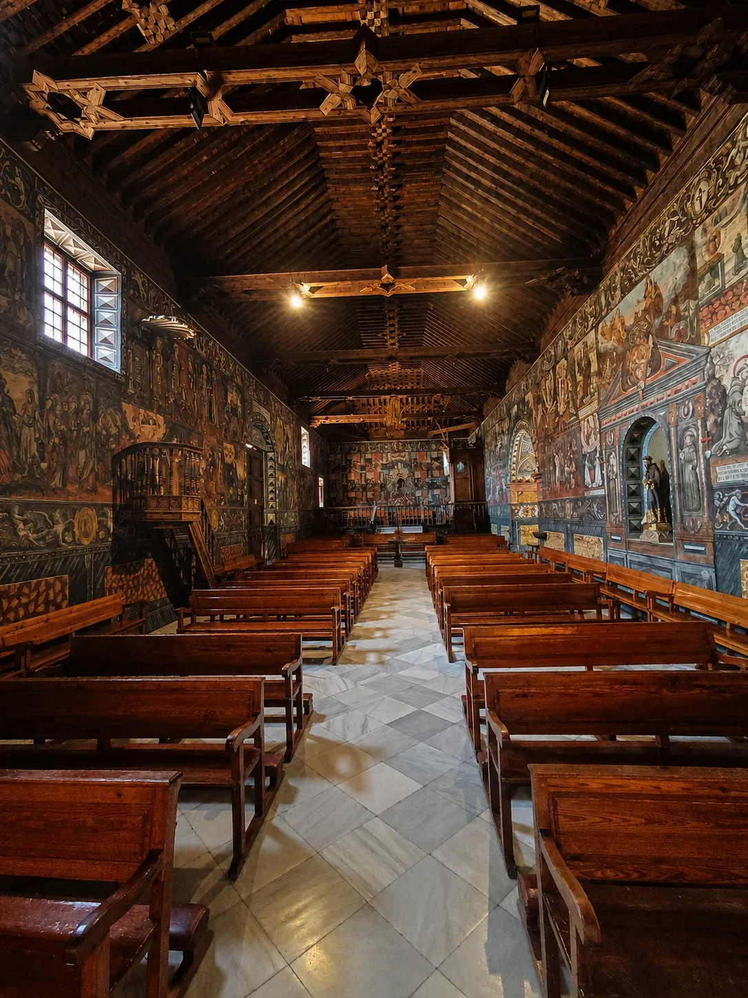 Portrait view along the pews beneath the carved wooden ceiling