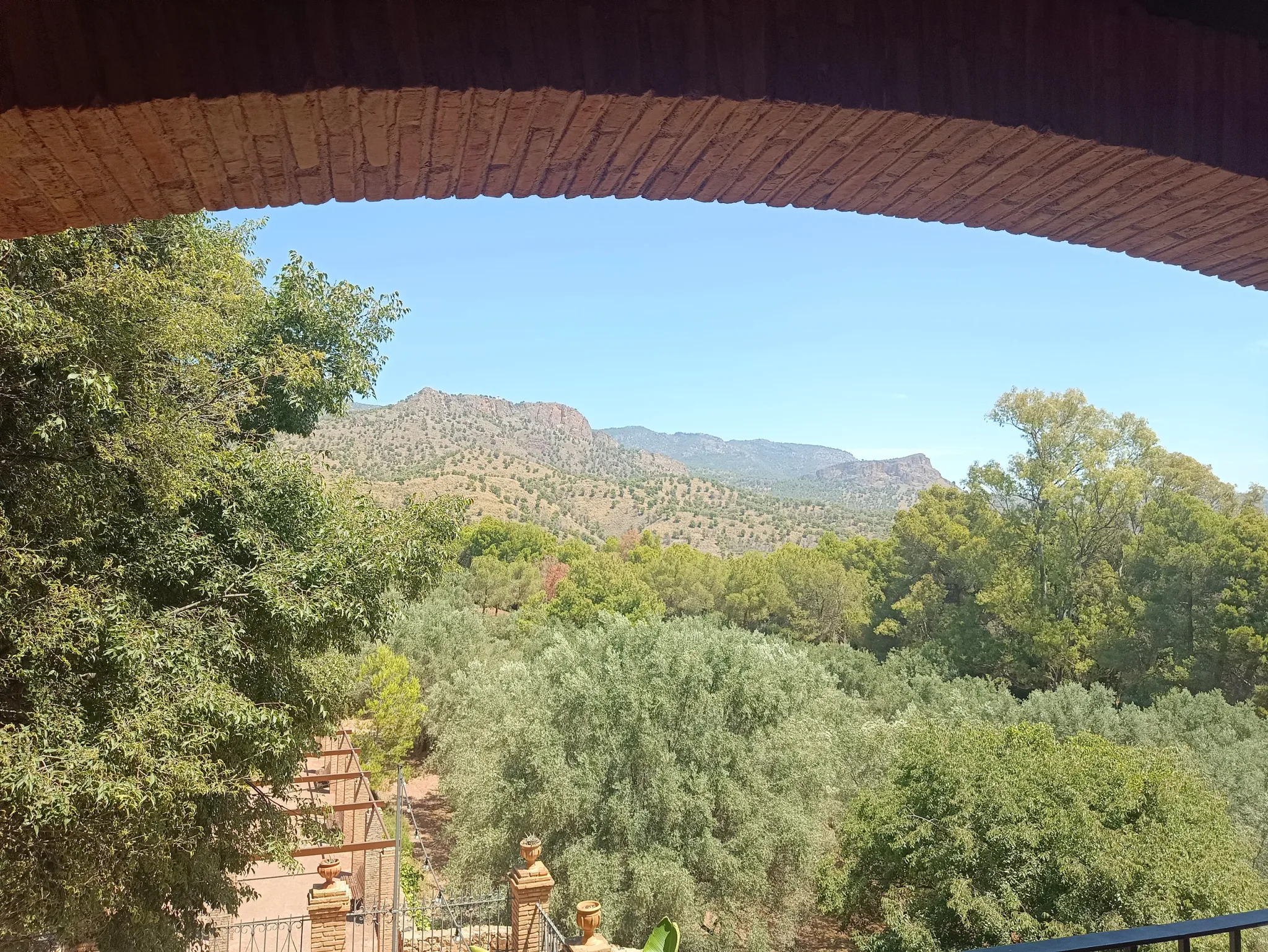 View of wooded Sierra Espuña hills framed by a brick arch at La Santa